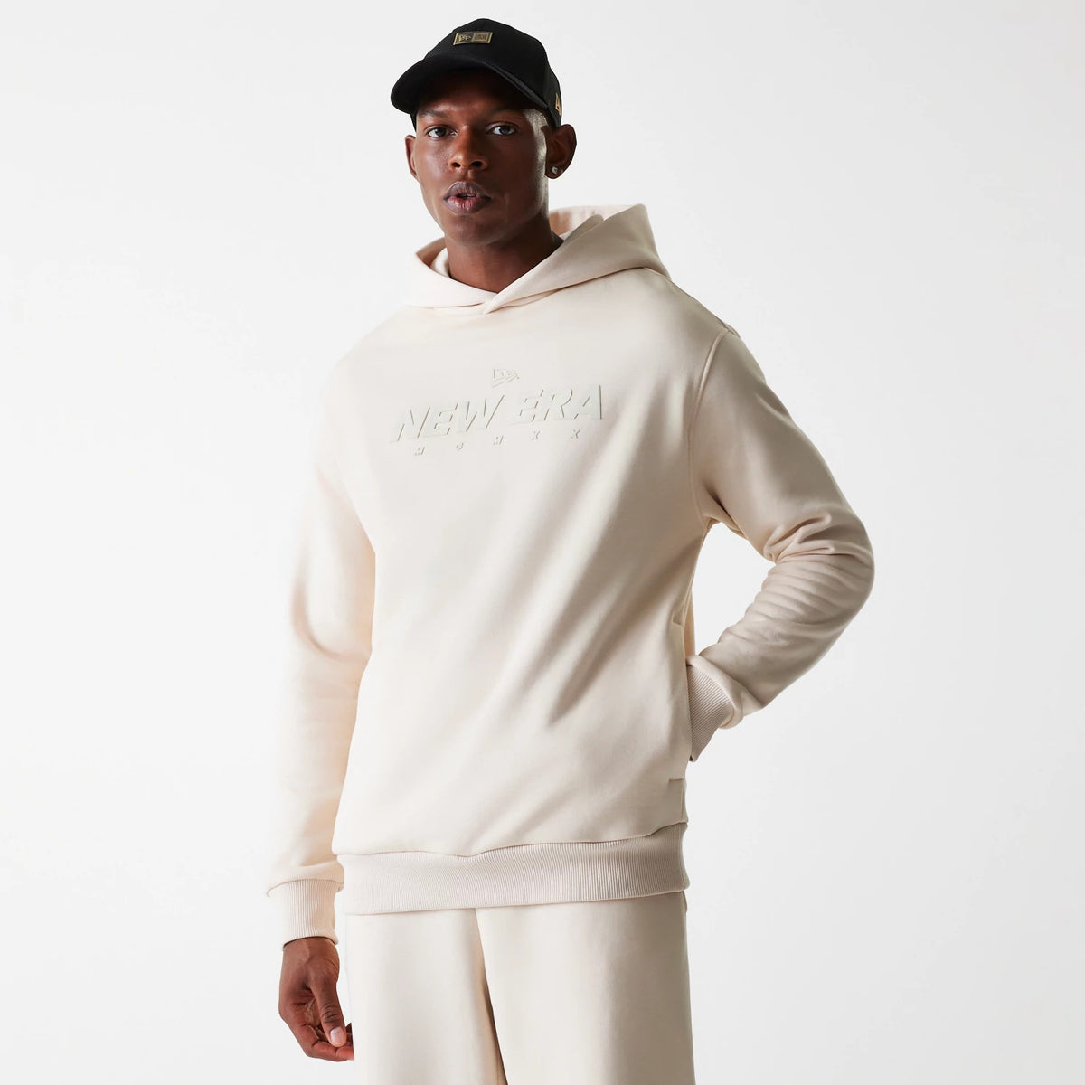 New Era Tech Light Beige Oversized Pullover Hoodie, front view showing a raised New Era logo centred on the chest, with a spacious hood and ribbed cuffs and hem around the light beige design.