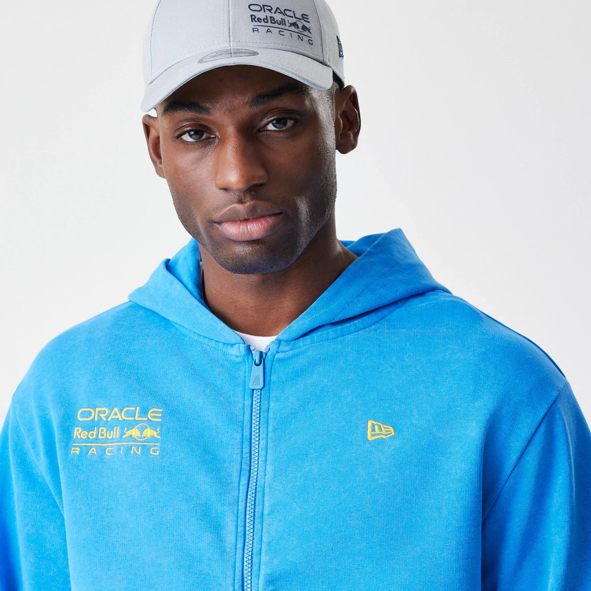 New Era Red Bull Racing Blue Oversized Full Zip Hoodie, front view on-model showing the blue hue with a full zip closure, yellow embroidered New Era logo on the chest, and Red Bull Racing branding on the left side.