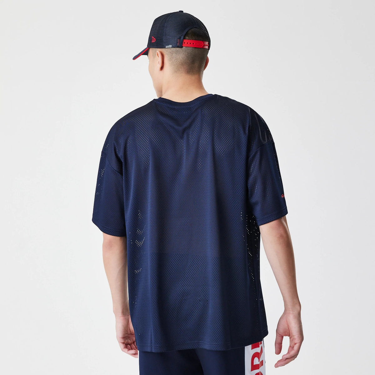 New Era Red Bull Racing Graphic Mesh Dark Blue Oversized T-Shirt, back view on a model with a dark cap, showing the textured mesh design covering the entire shirt and a small embroidered logo on the left sleeve.