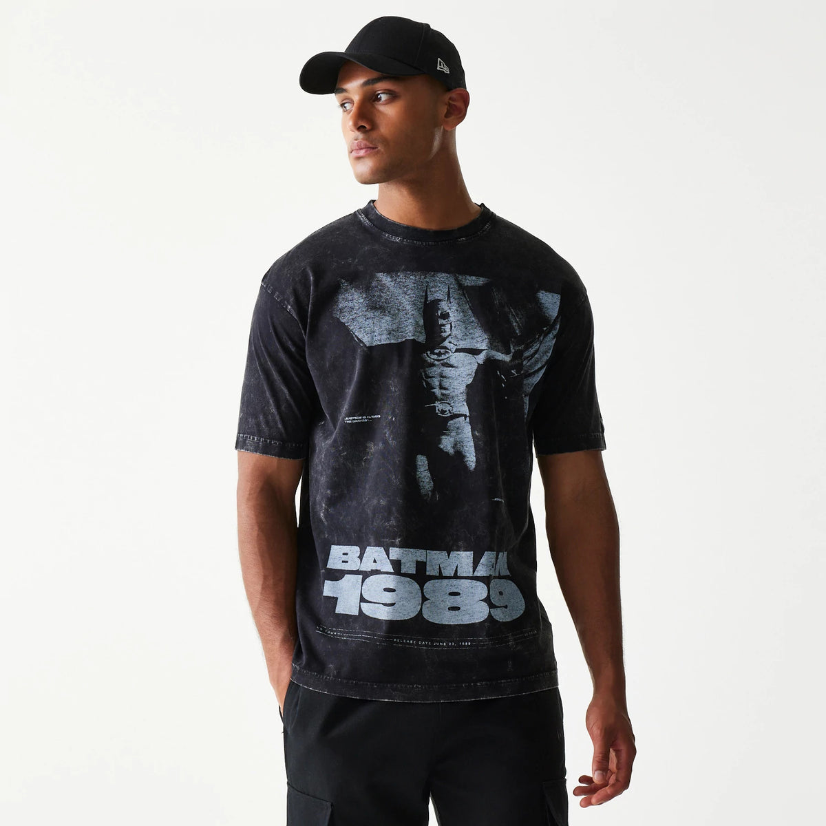 New Era Batman 1989 Black T-Shirt, front view on a model featuring a large graphic of Batman with outstretched wings across the chest and Batman 1989 text below in a contrasting light shade.