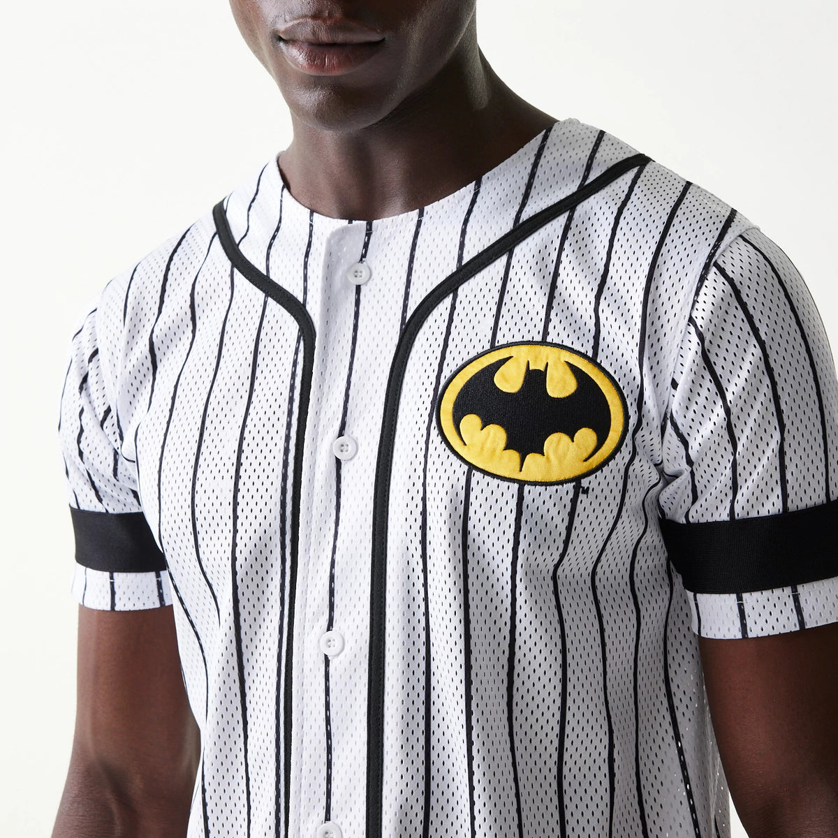 New Era Batman Pinstripe White Jersey, three-quarter view on a model showing the black embroidered Batman logo on the left chest, complemented by black piping along the front and sleeves.