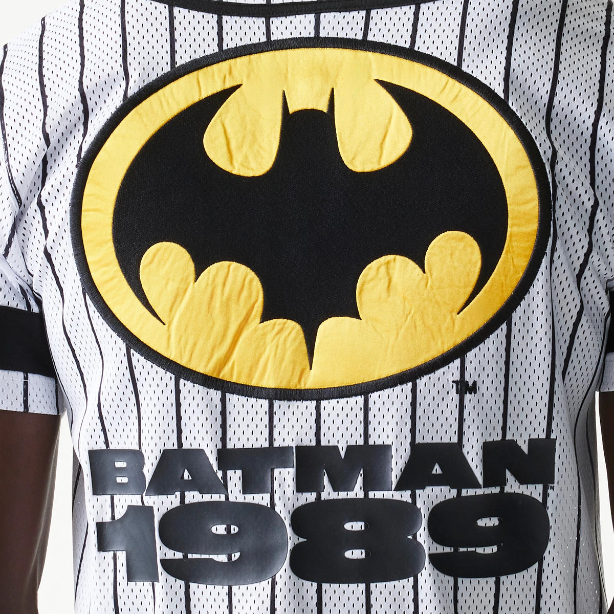 New Era Batman Pinstripe White Jersey, front view showing a large black and yellow Batman logo across the chest, with vertical black pinstripes and BATMAN 1989 lettering in black below.