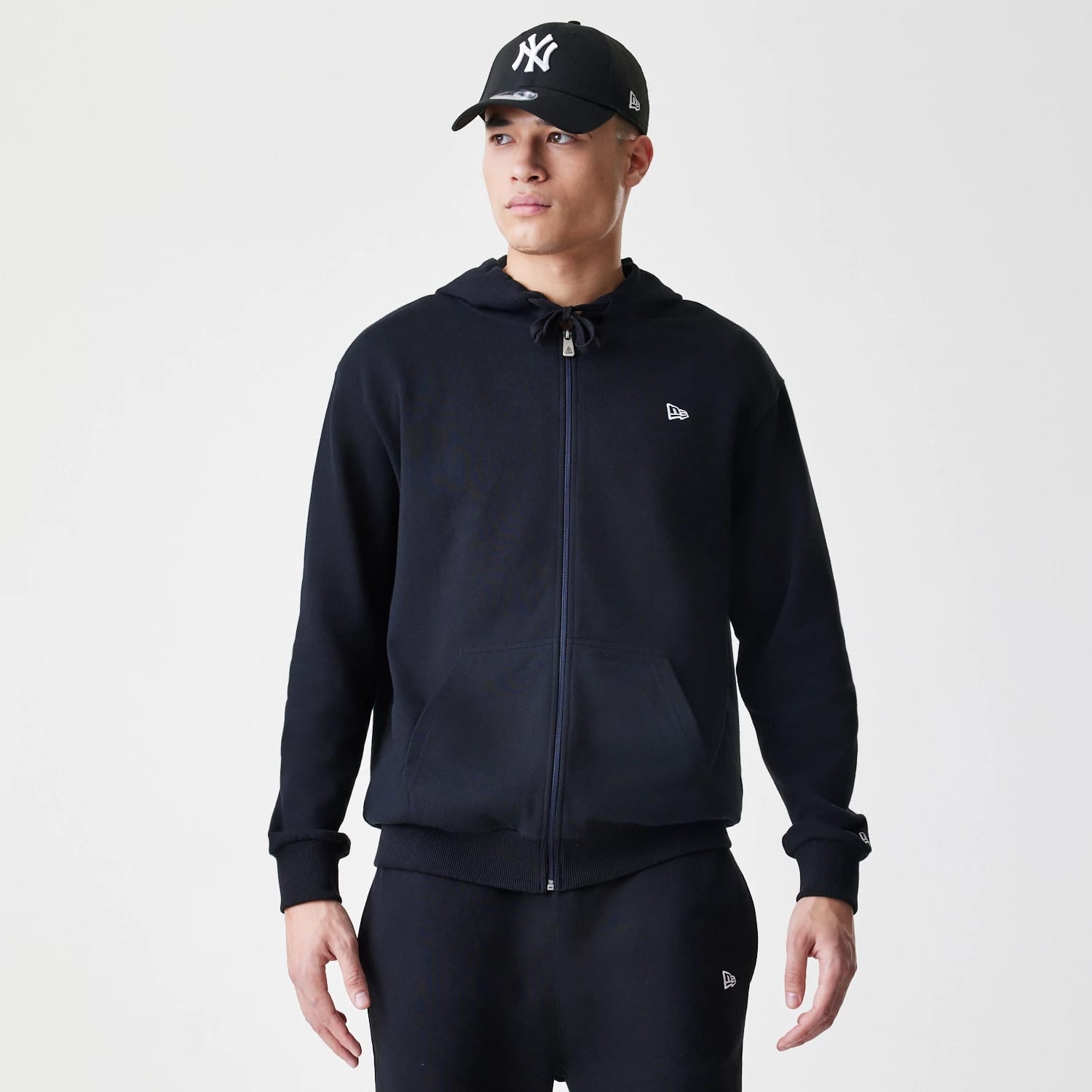 The Male model is wearing New Era Premium Essential Black Oversized Full Zip Hoodie 1