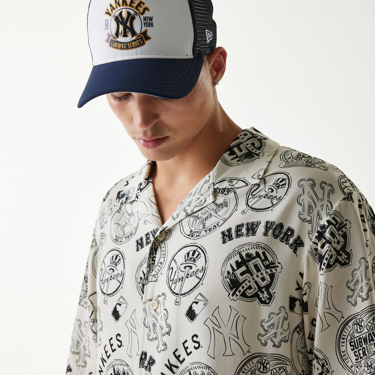 New Era MLB Subway Series All Over Print Open White Short Sleeve Shirt, front view on a model wearing a matching black and white cap, featuring various black New York Yankees logos and graphics across the shirt fabric.