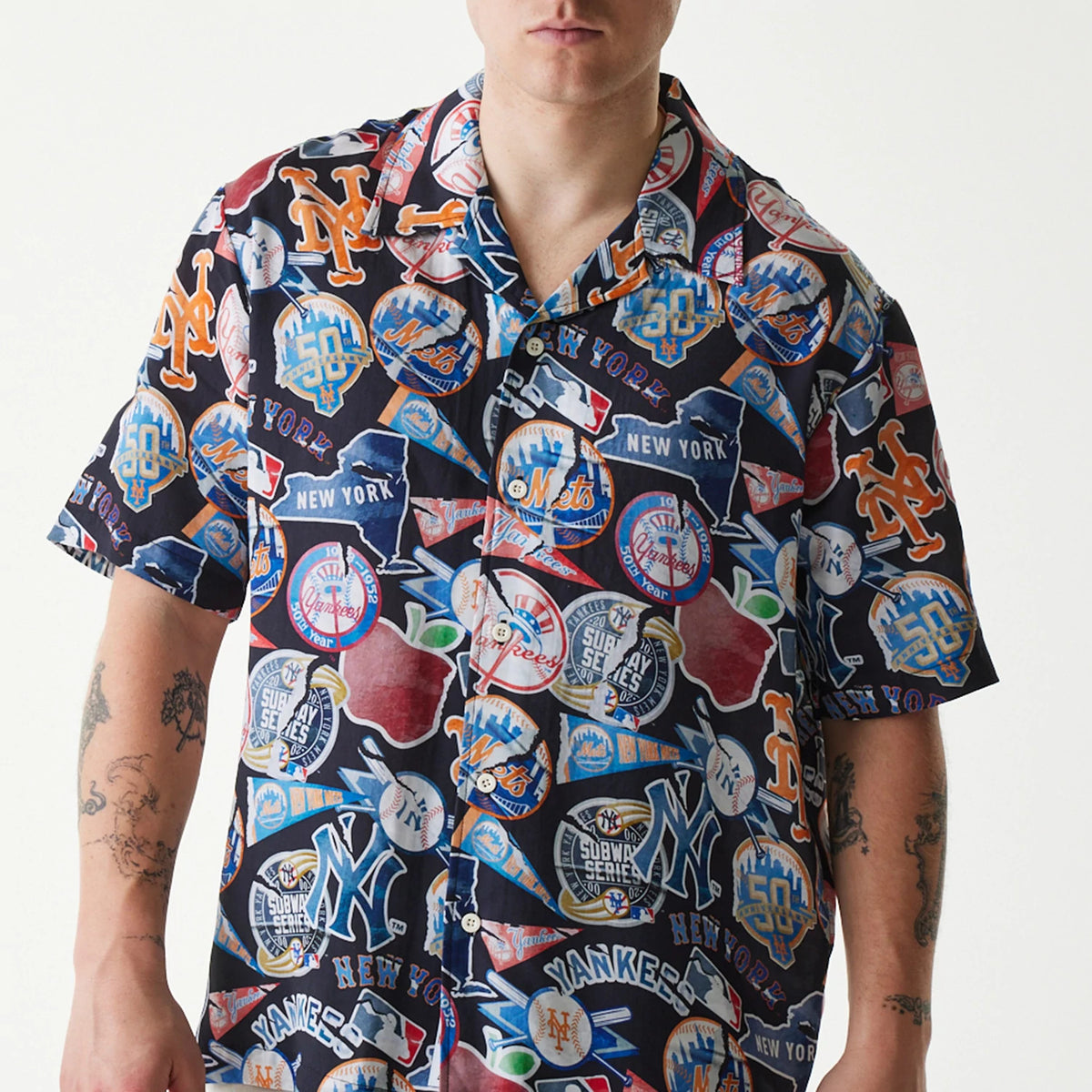 New Era MLB Subway Series All Over Print Navy Short Sleeve Shirt, front view on a model featuring an intricate collage of New York Yankees and Mets logos with colours, button-up design, and short sleeves.