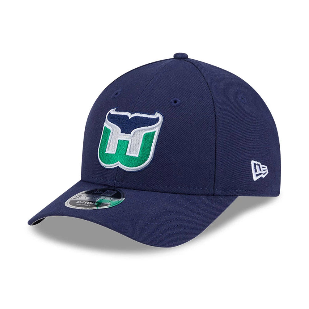 Hartford Whalers NHL Team Navy New Era 9FORTY M-Crown Adjustable Cap, three-quarter view showing the raised green and white embroidered team logo on the front panel, curved navy visor with a 9FORTY size sticker.