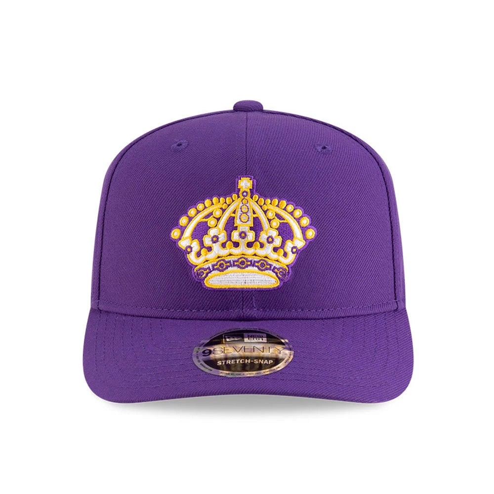 LA Kings NHL Team Purple New Era 9SEVENTY Stretch Snap Adjustable Cap, front view showing a detailed gold and white crown logo embroidered on the structured purple front panels, with a 9SEVENTY size sticker on the flat purple visor.