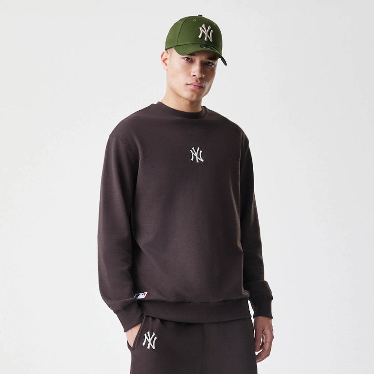 New Era New York Yankees MLB Midi League Essential Dark Brown Oversized Crew Neck Sweater, front view on a model styled with a matching dark brown design and white Yankees logo embroidered on the chest.