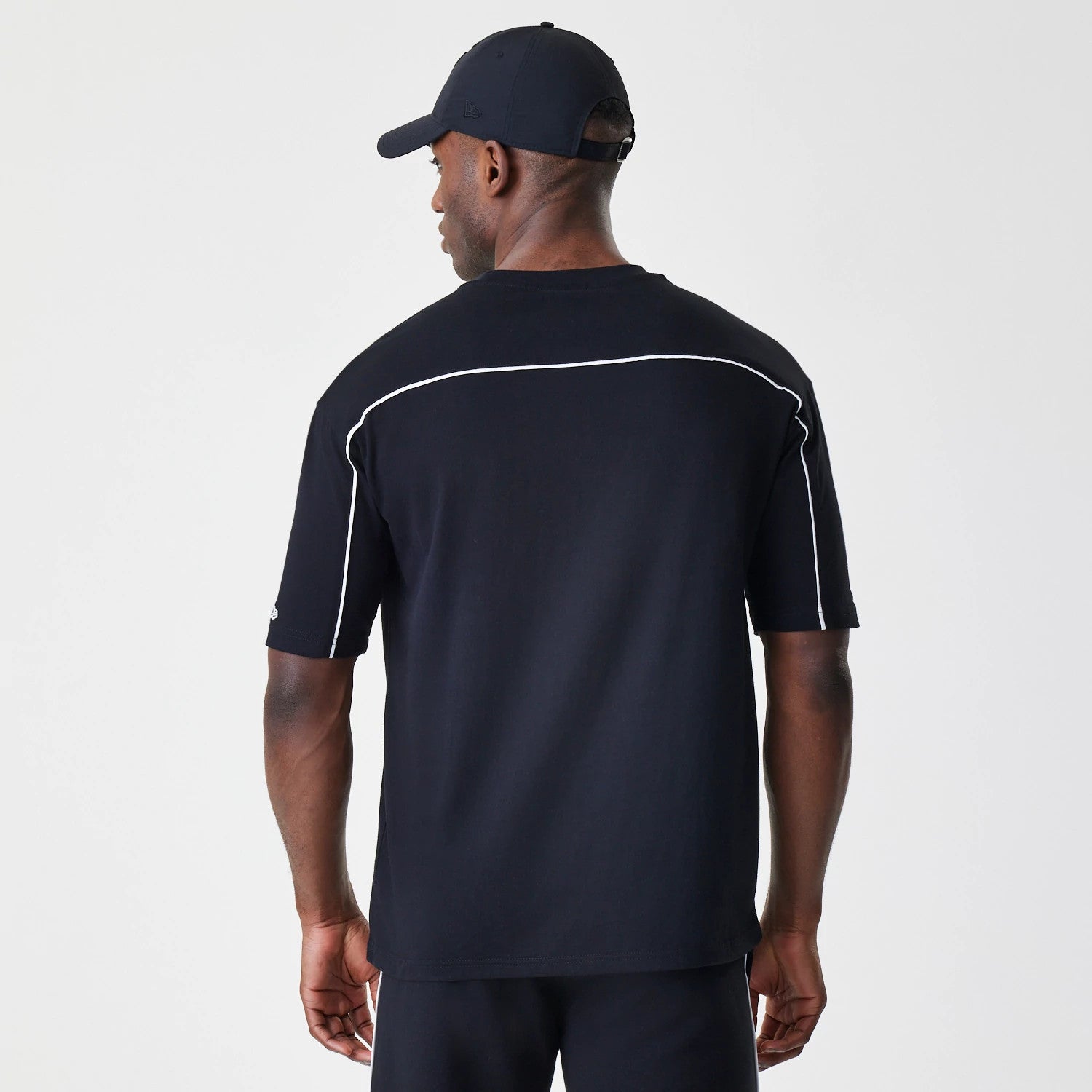 New Era Chicago Bulls NBA Piping Stripe Black Oversized T-Shirt, back view on-model showing distinctive white piping running horizontally across the upper back and down the sleeves on a black oversized fit.
