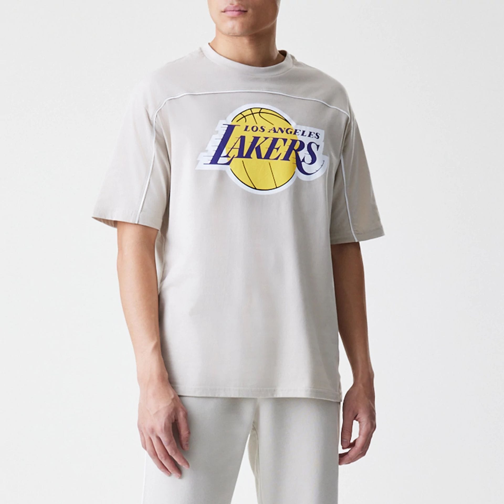 The Male model is wearing LA Lakers NBA Piping Light Beige Oversized T-Shirt 1