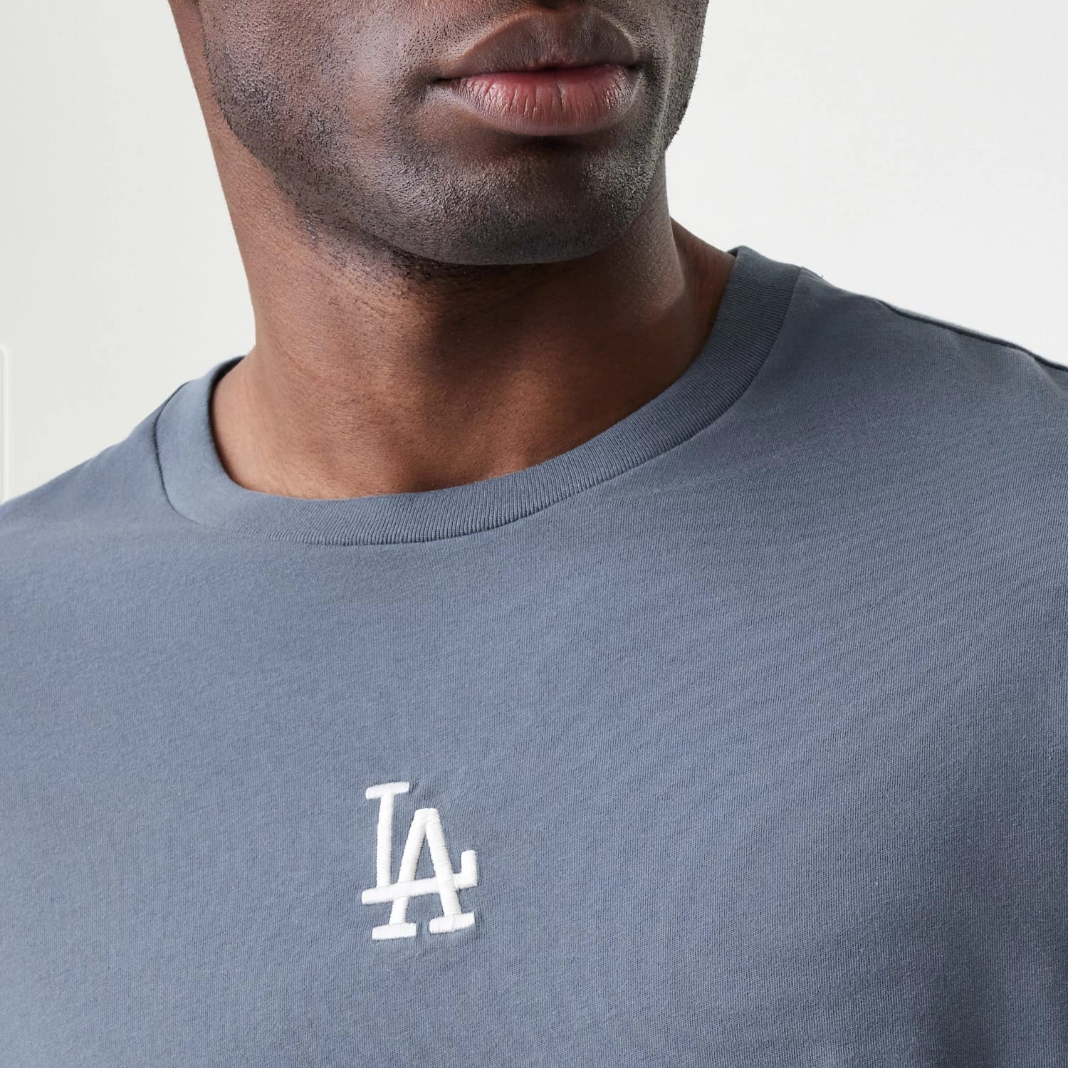 New Era LA Dodgers MLB Midi League Essential Dark Grey Oversized T-Shirt, front view on-model showing the crew neck line and a white embroidered LA logo prominently placed on the chest.