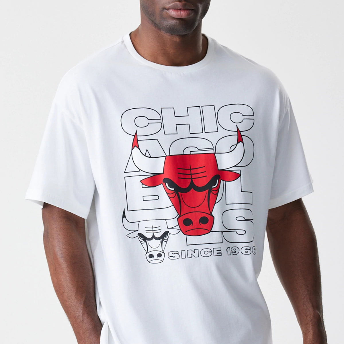 New Era Chicago Bulls NBA Outline Graphic White Oversized T-Shirt, front view on-model showing the large outlined graphic of the Bulls logo in red and black across the chest with lettering behind and SINCE 1966 printed at the bottom.