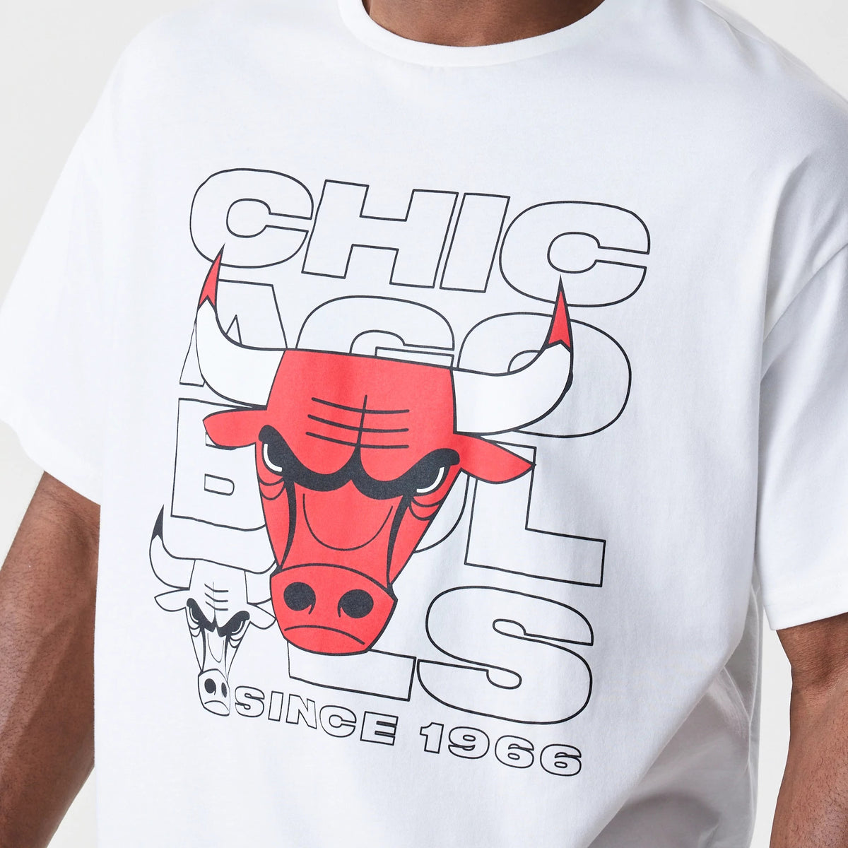 New Era Chicago Bulls NBA Outline Graphic White Oversized T-Shirt, front view showing a large printed red bull logo centred over outlined lettering and the phrase Since 1966 below, worn casually on a model.