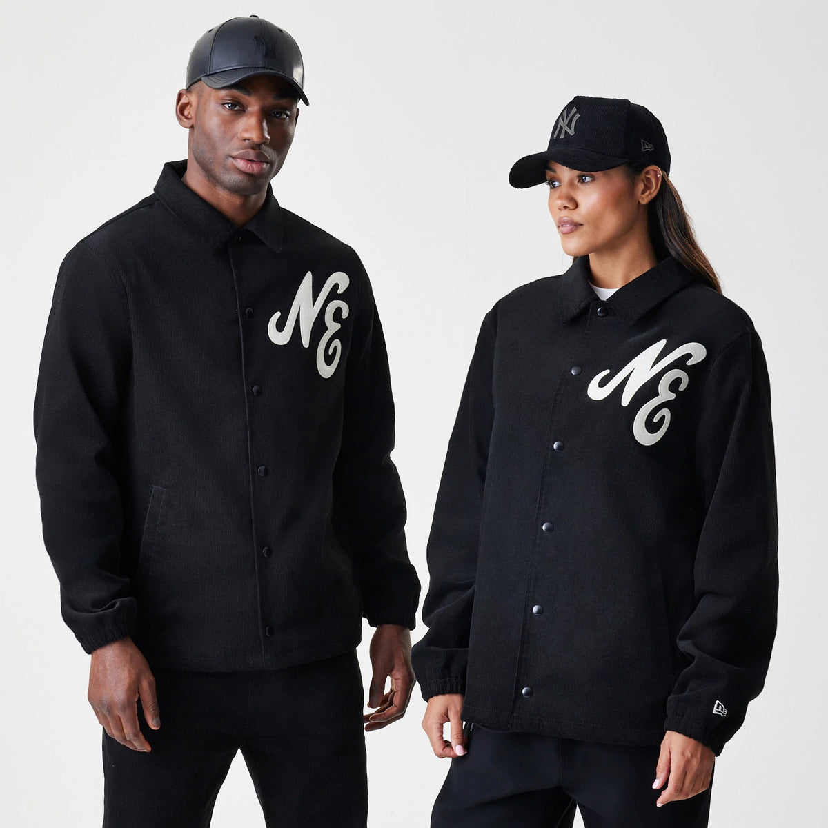 New Era Cord Black Coaches Jacket, front view on-model showing the white embroidered NE lettering on the chest, button closure down the middle, and a small embroidered New Era logo on the sleeve near the cuff.