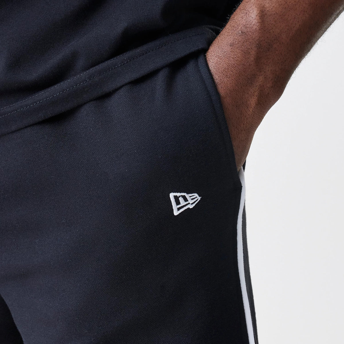 New Era Chicago Bulls NBA Piping Navy Joggers, close-up showing the white embroidered New Era flag logo on the left thigh and white piping running down the side seam for added style detail.