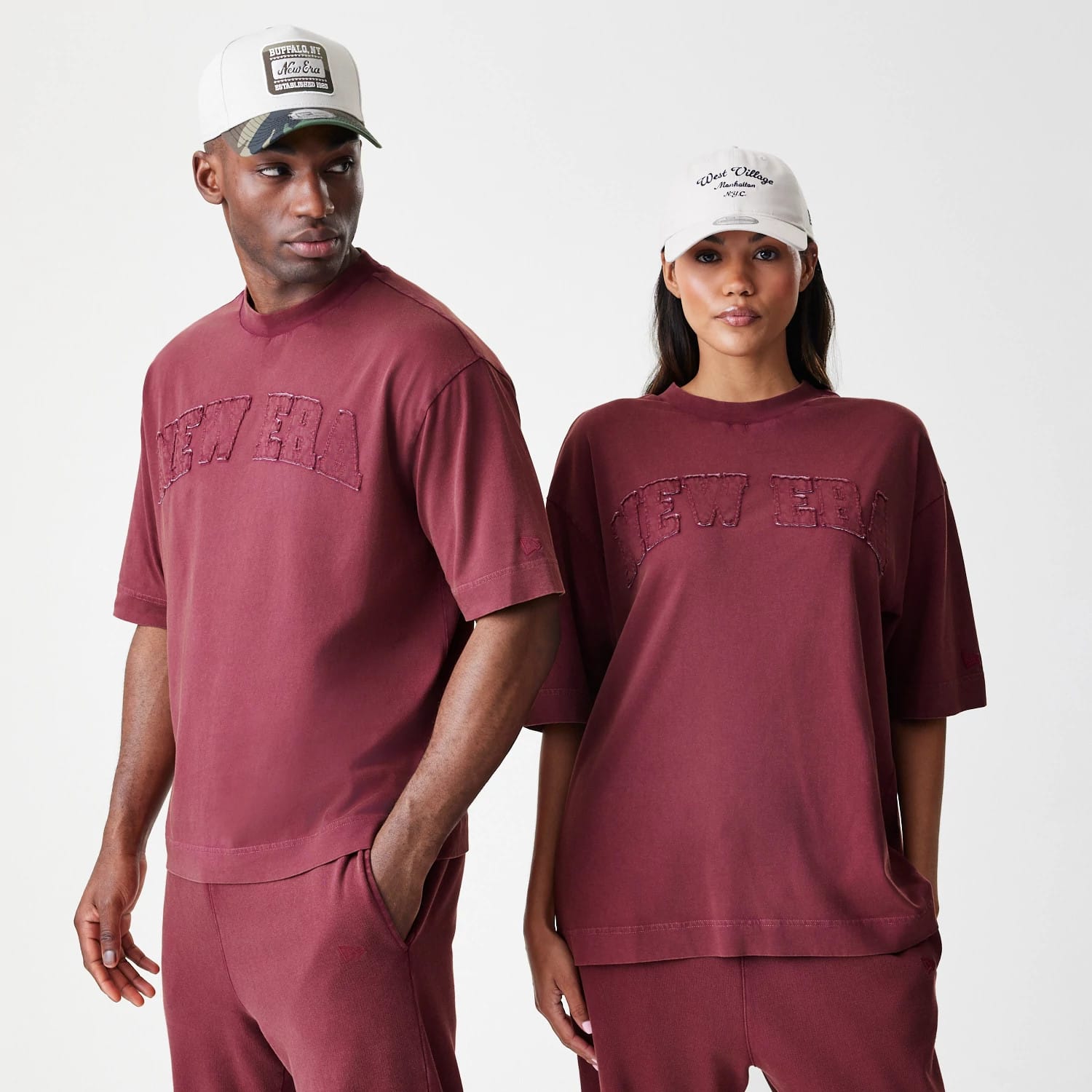 New Era Washed Dark Red Oversized T-Shirt, front view showing an embroidered New Era logo in matching dark red across the chest, with short sleeves and a relaxed fit, styled on-model with matching trousers.