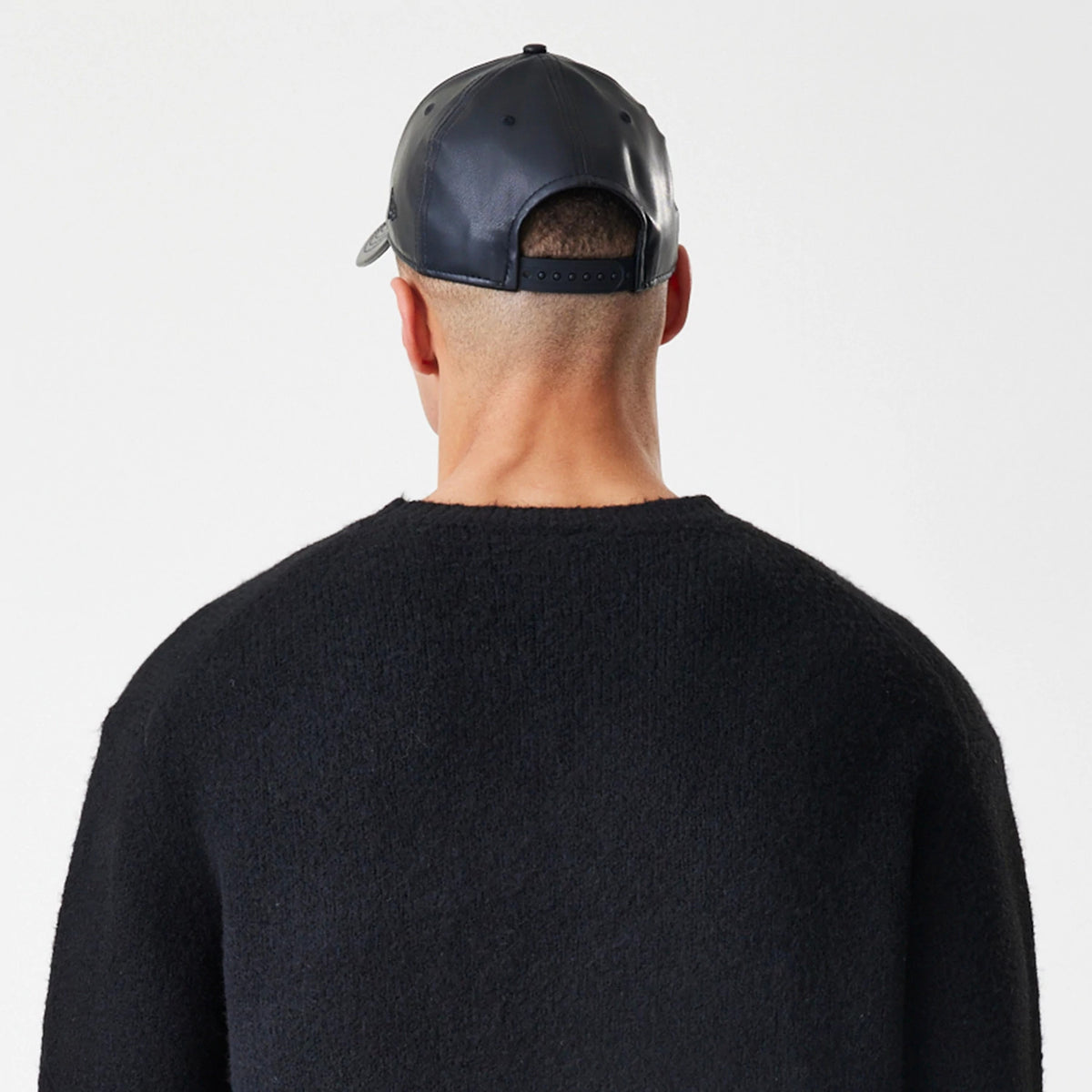 New Era Knit Black Knitted Sweater, rear view on a model featuring a textured knit fabric with a crew neck design, showcasing a clean and simple silhouette ideal for layering or stand-alone wear.