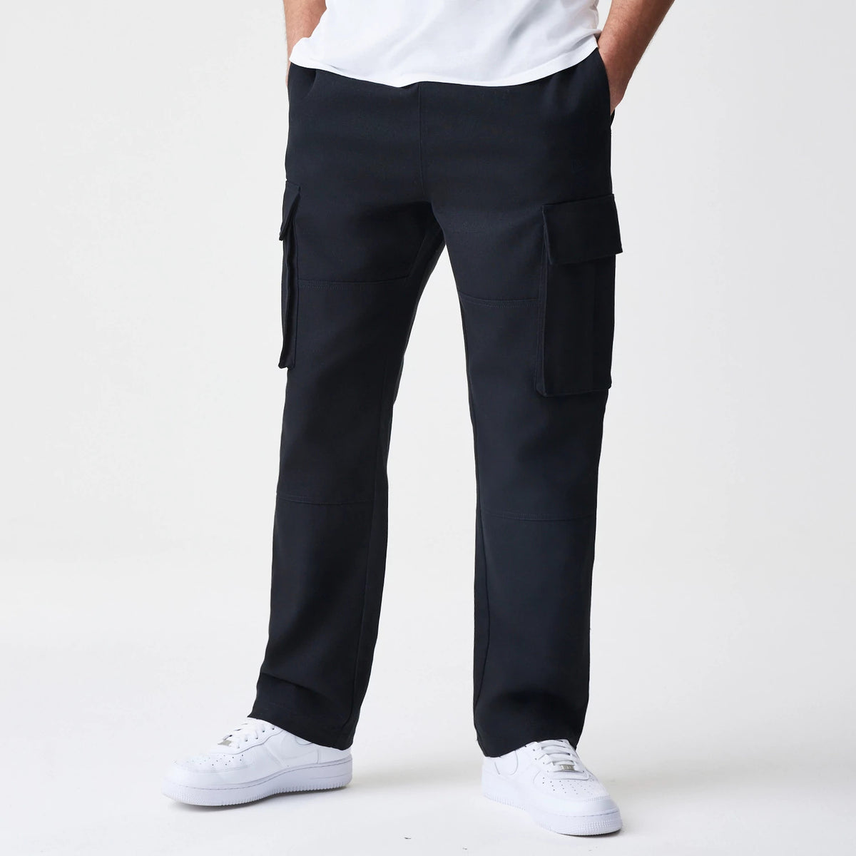 New Era Cargo Black Straight Leg Trousers, front view showing multiple cargo pockets on both legs, straight cut design and tailored fit in solid black fabric, paired with white sneakers.