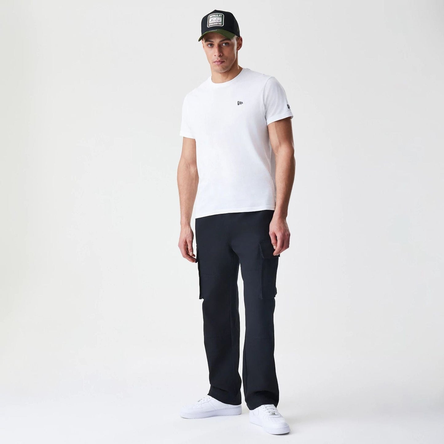 New Era Cargo Black Straight Leg Trousers, on-model view showing two spacious side pockets on each leg, with a relaxed fit and straight cut from waist to hem, styled with a white T-shirt and trainers.