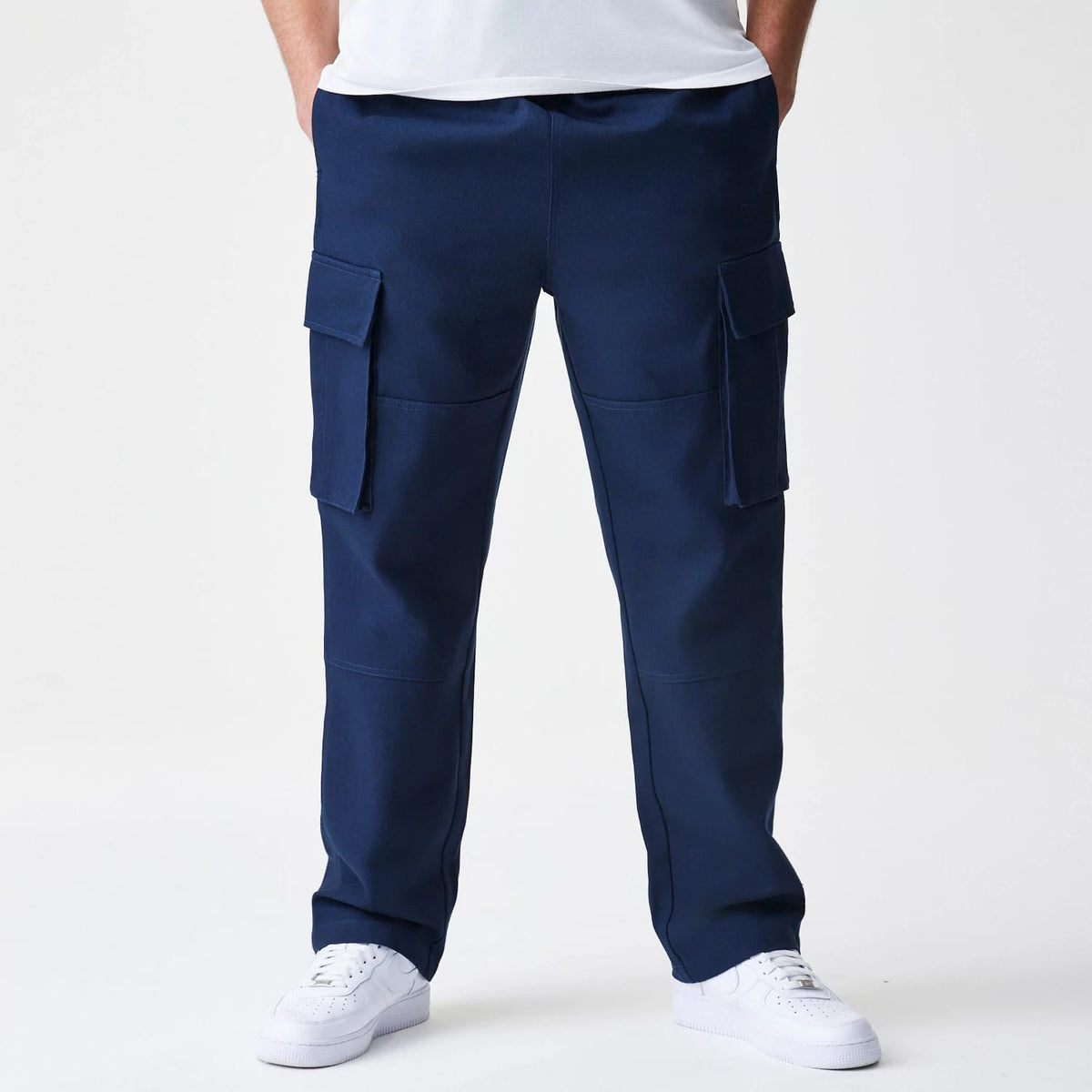 New Era Navy Straight Leg Cargo Trousers, front view with large flap pockets on each thigh, displaying a mid-rise waistband, a finish, and a relaxed straight leg fit worn with white trainers.