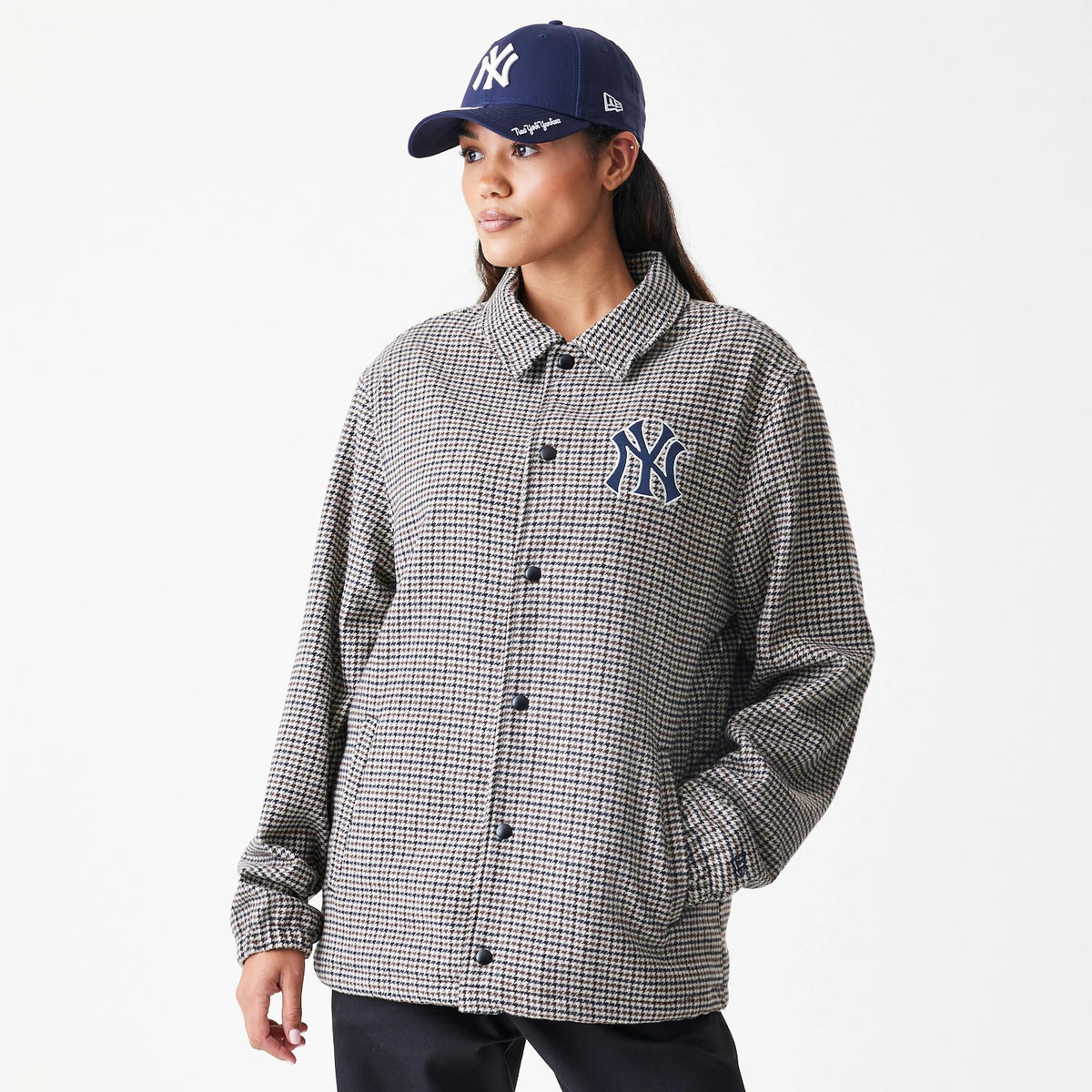 New Era New York Yankees MLB Check Brown Jacket, front view on a model styled with a navy cap, showing a button-up front and an embroidered New York Yankees logo on the upper left chest of the check-patterned jacket.