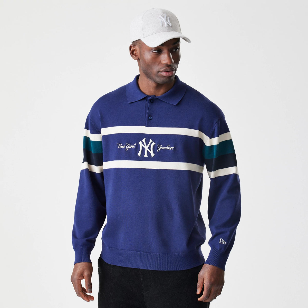 New Era New York Yankees MLB Knit Navy Rugby Shirt, front view on a model with the New York Yankees logo embroidered in white on the centre chest, featuring navy and white horizontal stripes on the arms and the New Era flag logo on the left sleeve.