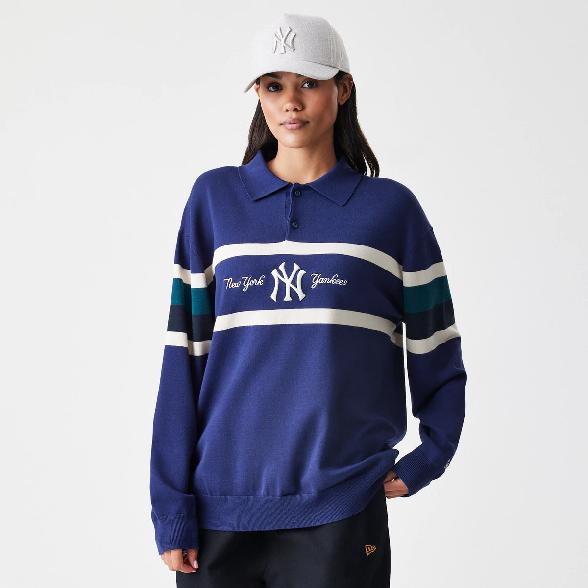 New Era New York Yankees MLB Knit Navy Rugby Shirt, front view on a model with a cap, featuring white and teal stripe across the chest and sleeves, an embroidered New York Yankees logo in the centre, and a classic polo collar.
