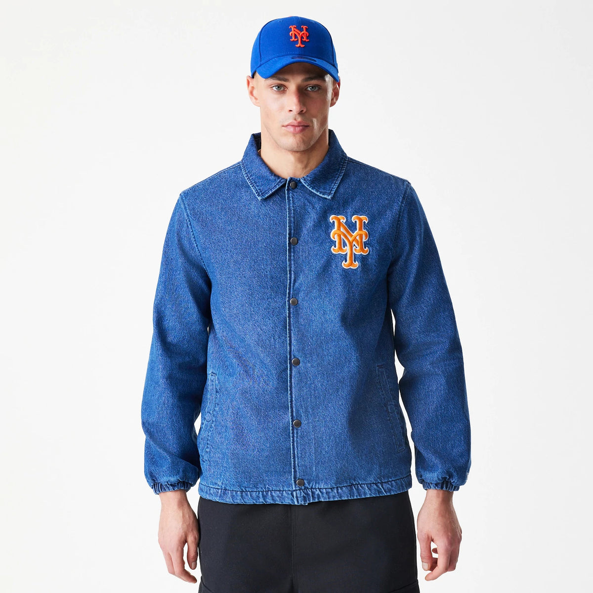 New Era New York Mets MLB Denim Dark Blue Coaches Jacket, front view showing a orange and white embroidered Mets logo on the left chest, button closures down the front, worn by a model with a blue cap with matching logo.