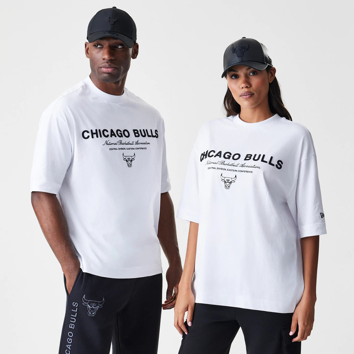 New Era Chicago Bulls NBA Linear White T-Shirt, front view on models showing the black printed Chicago Bulls logo and text centred on the chest, with a New Era logo embroidered on the sleeve edge.