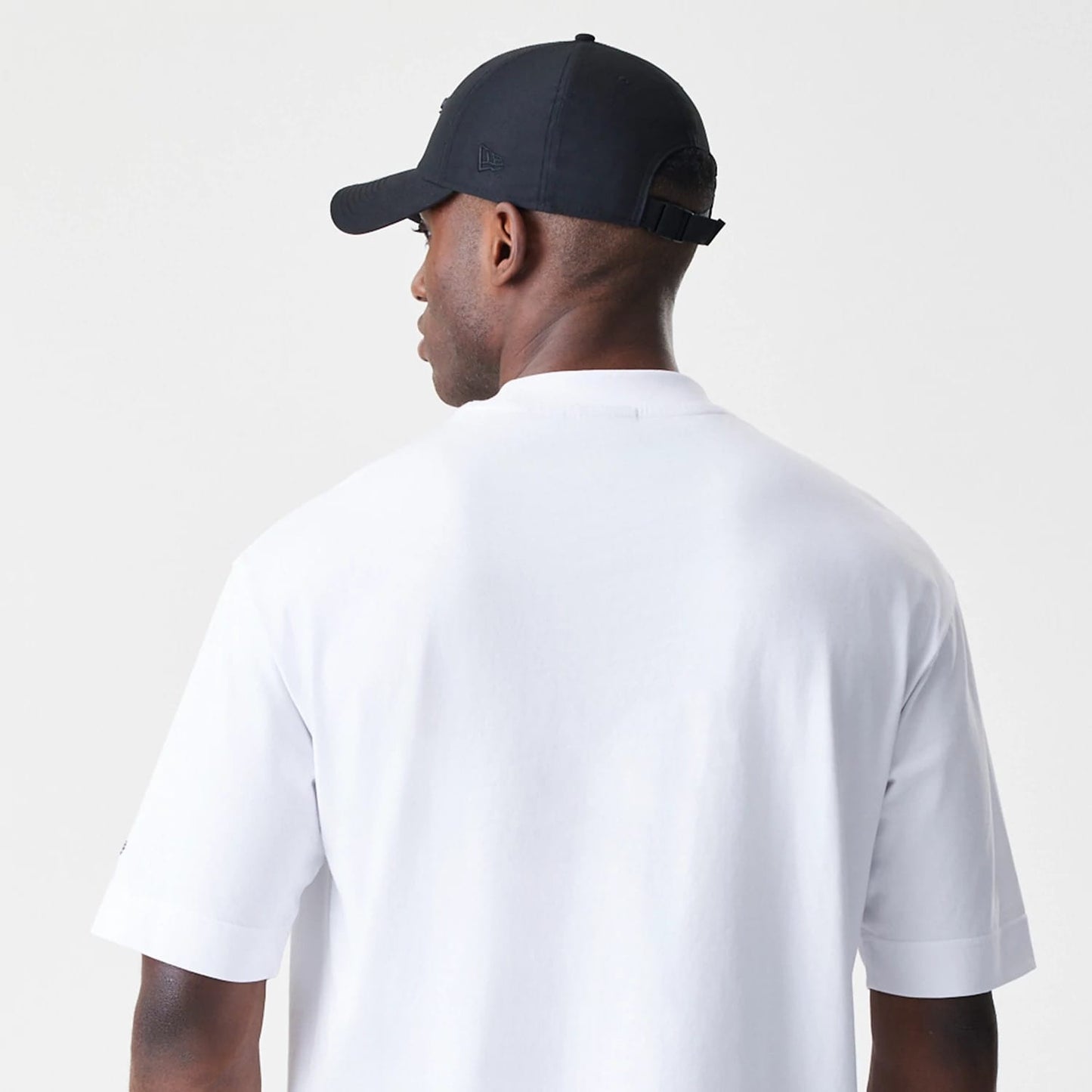 New Era Chicago Bulls NBA Linear White T-Shirt, back view on-model with a plain white design, short sleeves and a crew neck, paired with a black New Era cap with an embroidered logo on the side.