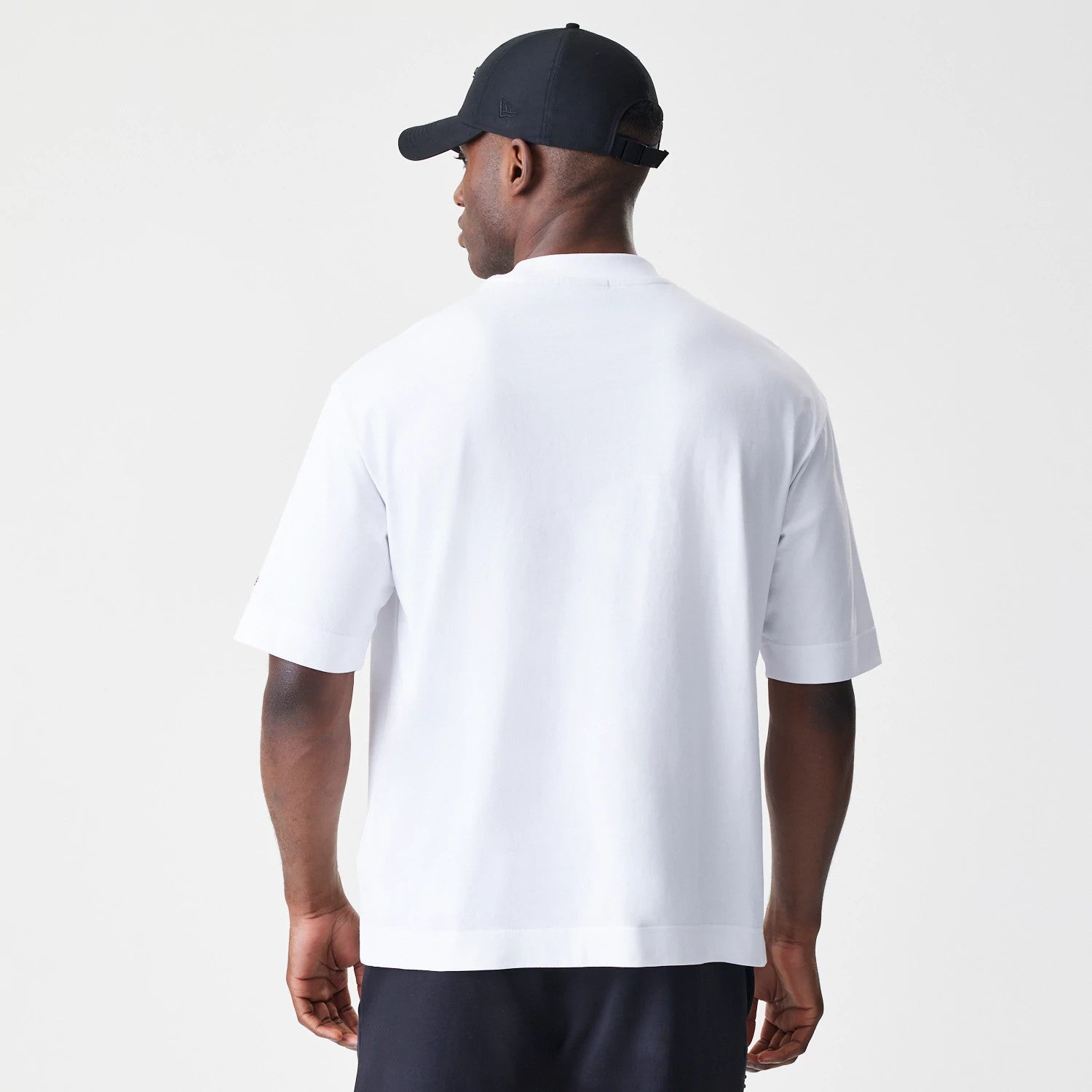 New Era Chicago Bulls NBA Linear White T-Shirt, back view on a model wearing a black cap, showcasing the plain white fabric and relaxed fit with the sleeves slightly covering the arms.