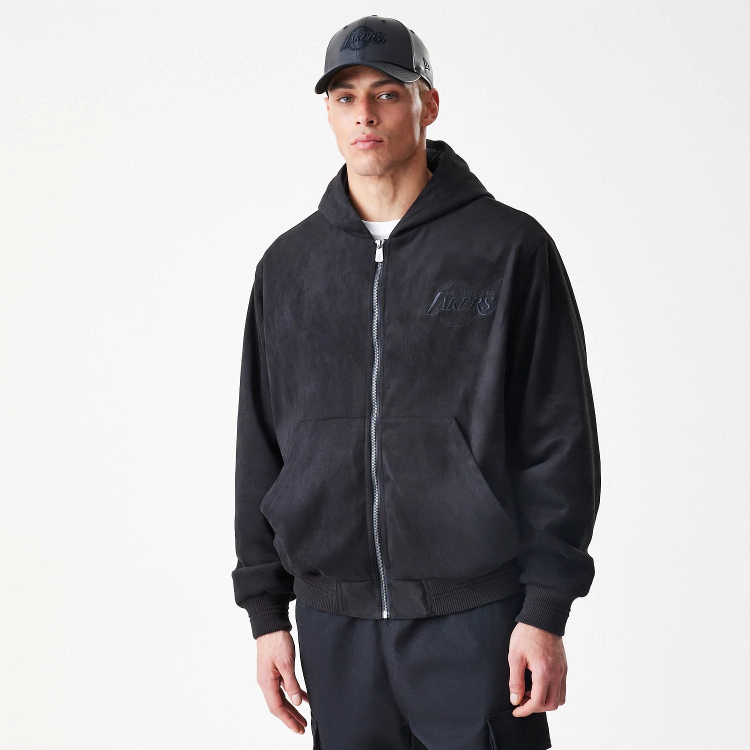 New Era LA Lakers NBA Suede Black Hooded Jacket, front view on-model showing the full zip closure and an embroidered Lakers logo on the left chest with a matching black cap on the model.