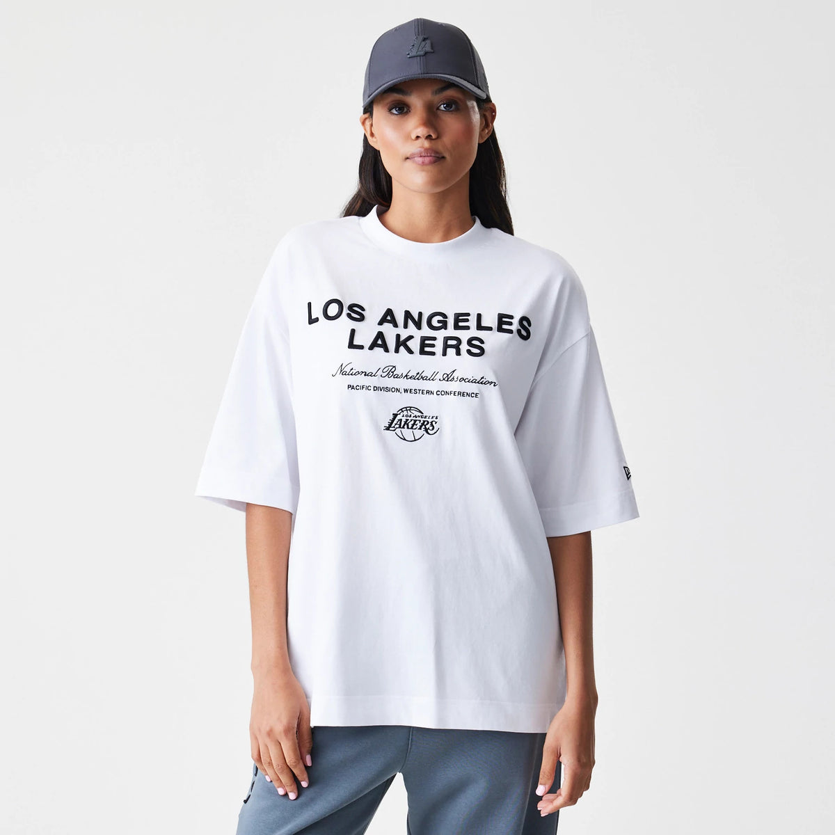 New Era LA Lakers NBA Linear White T-Shirt, front view on-model featuring black Los Angeles Lakers lettering across the chest, an embroidered LA Lakers logo underneath, and a small New Era logo on the left sleeve.