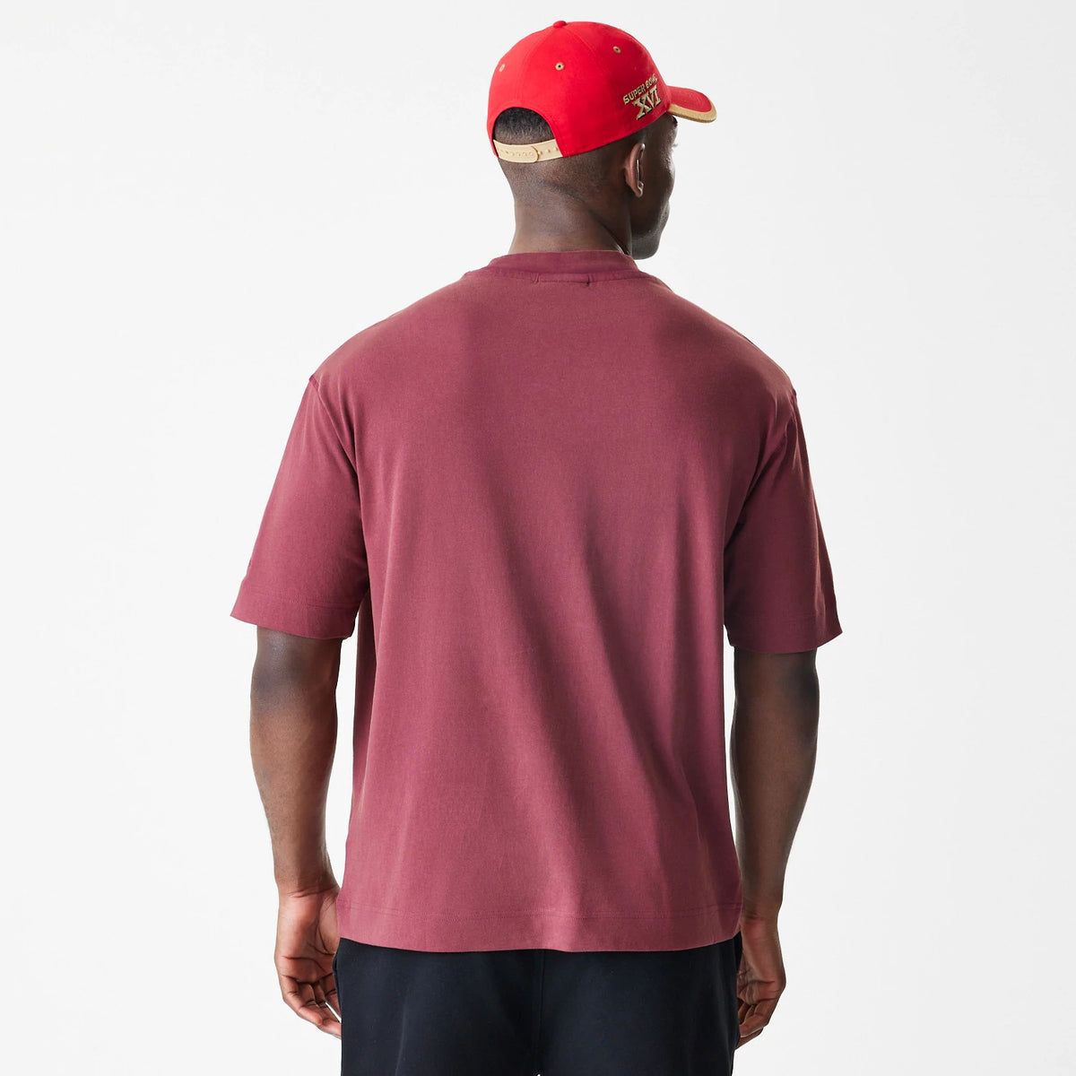 New Era San Francisco 49ers NFL Washed Boxy Dark Red Oversized T-Shirt, back view on a model showing the plain back panel and relaxed fit, paired with a bright red cap with embroidered Super Bowl XVI text.