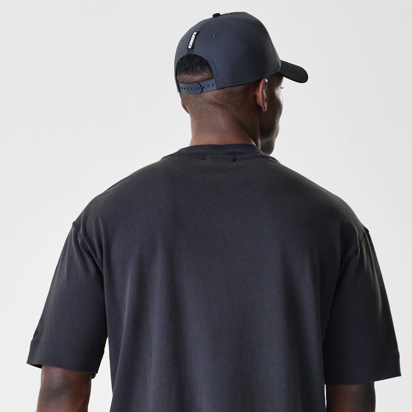 New Era Kansas City Chiefs NFL Washed Boxy Black Oversized T-Shirt, back view on a model wearing a matching cap, featuring a plain black design with relaxed boxy fit across the shoulders and sleeves.