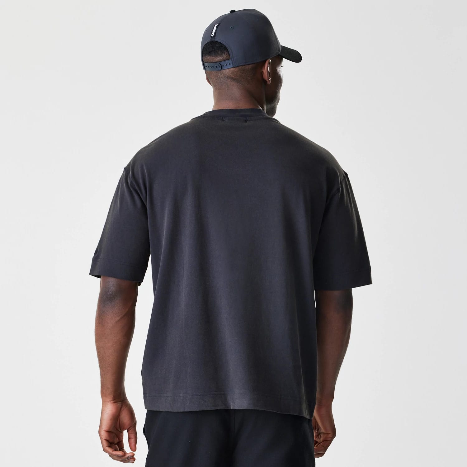 New Era Kansas City Chiefs NFL Washed Boxy Black Oversized T-Shirt, back view on-model showcasing the plain black fabric with a relaxed fit and dropped shoulder sleeves, styled with a matching black cap.