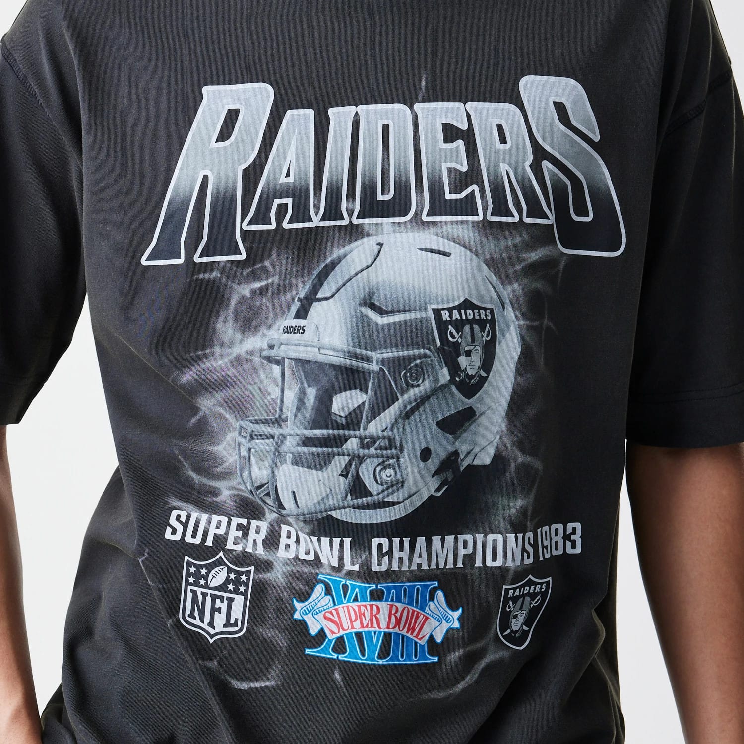 New Era Las Vegas Raiders NFL Washed Boxy Dark Grey Oversized T-Shirt, front view showing a large printed graphic of a Raiders helmet, Raiders lettering above and Super Bowl Champions 1983 text below with NFL and Super Bowl logos.
