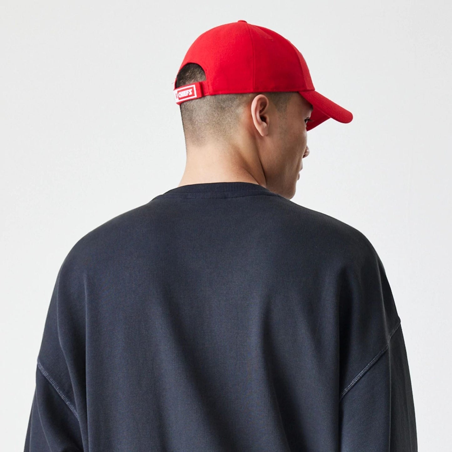 New Era Kansas City Chiefs NFL Washed Boxy Black Oversized Crew Neck Sweater, back view on a model wearing a black sweater, showing the relaxed fit and ribbed knit collar with dropped shoulder seams.