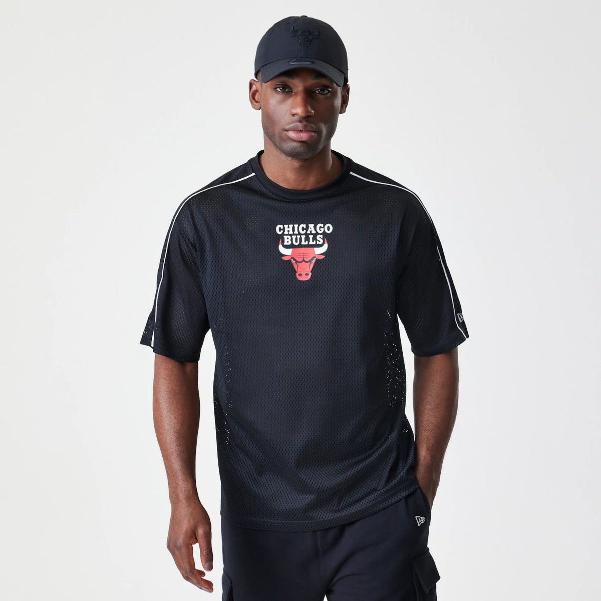 New Era Chicago Bulls NBA Piping Black Oversized T-Shirt, front view on-model showing the red and white Chicago Bulls logo centred below the neckline, with white piping along the shoulders and a small embroidered New Era logo on the left sleeve.