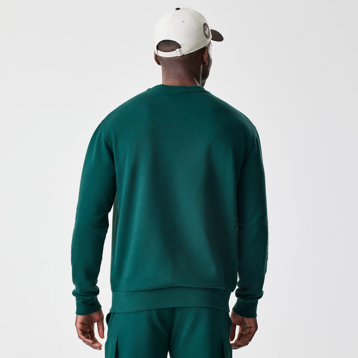 New Era LA Dodgers MLB Script Dark Green Crew Neck Sweater, back view on a model wearing matching dark green trousers, showing the simple crew neck and long sleeves with ribbed cuffs and waistband.