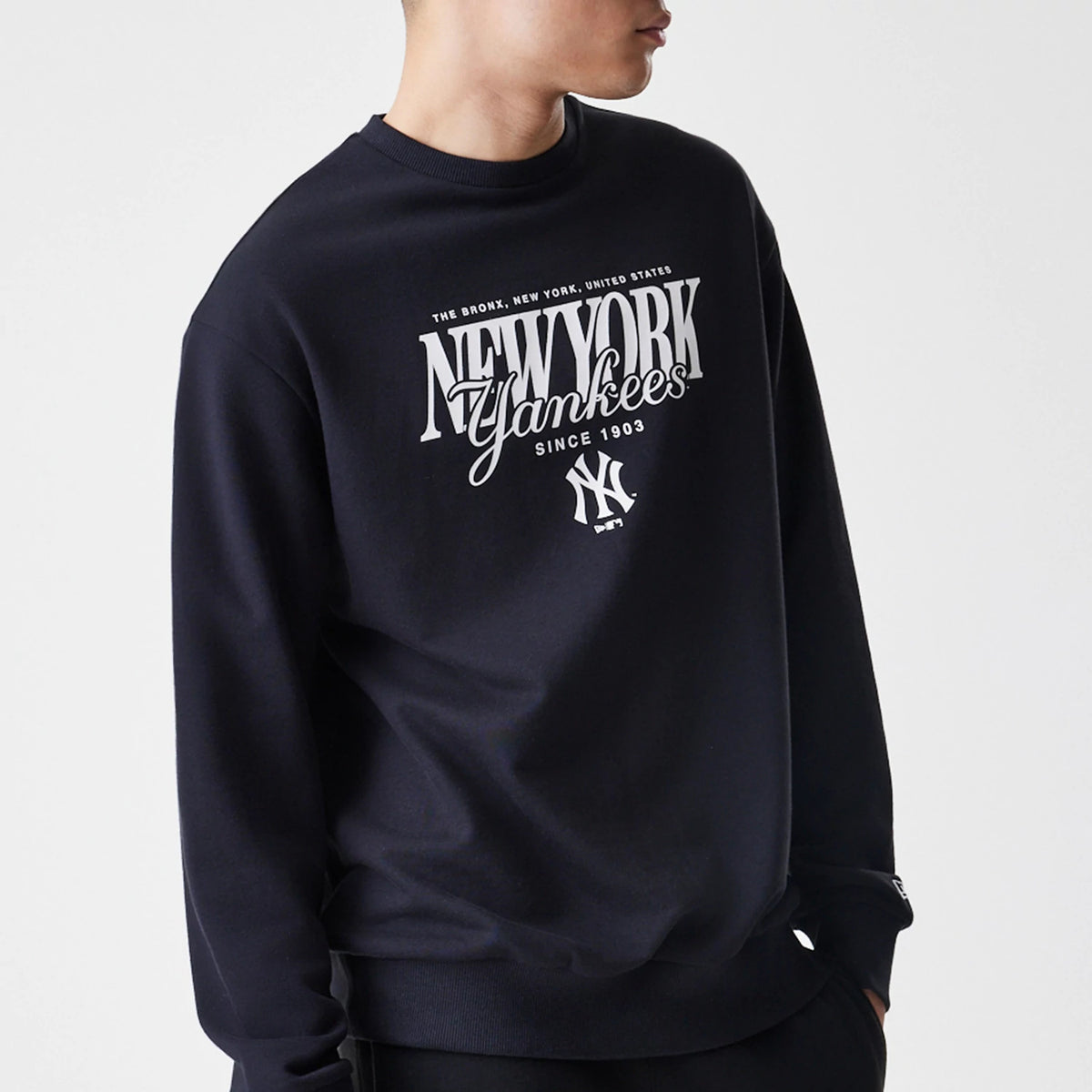 New Era New York Yankees MLB Script Black Crew Neck Sweater, front view on a model with a ribbed neckline showing white New York Yankees and NY logos, featuring since 1903 lettering across the chest.