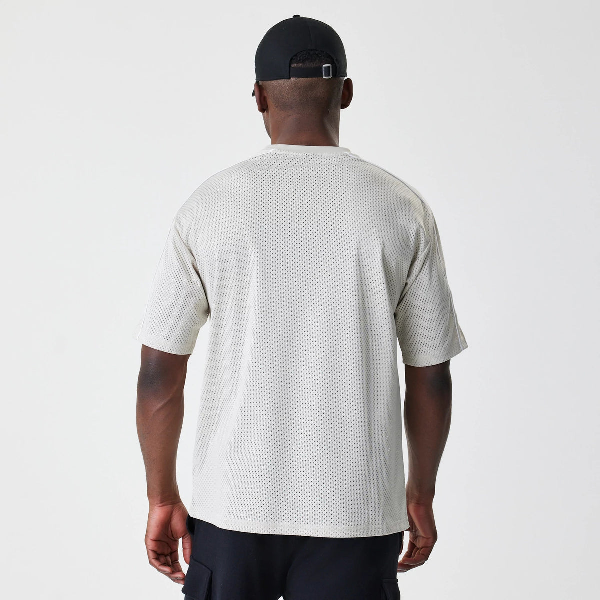 New Era LA Lakers NBA Piping Light Beige Oversized Mesh T-Shirt, back view on a model wearing a black cap, showing the light beige mesh texture with a loose fit draping over the shoulders and arms.