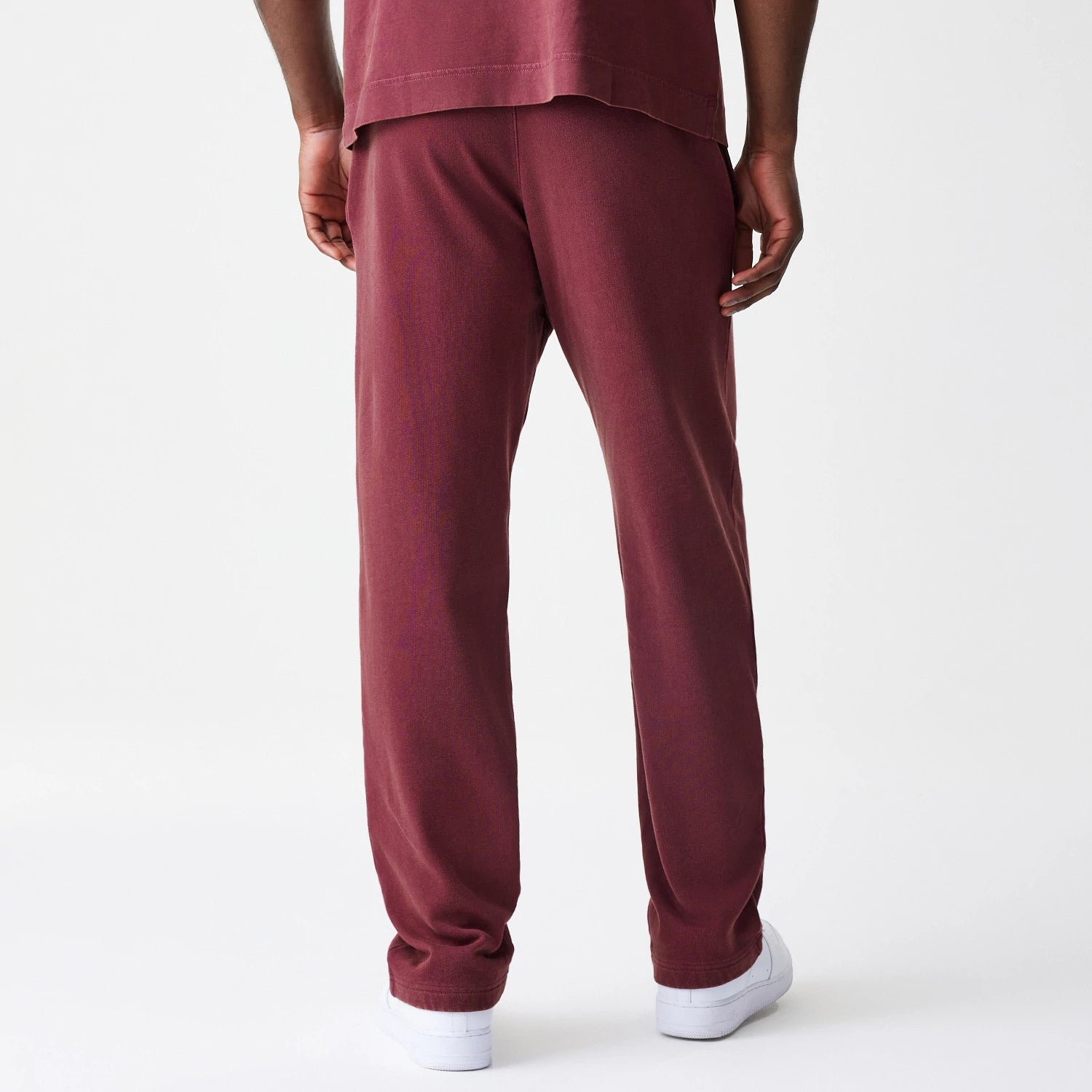 New Era Washed Dark Red Straight Leg Joggers, back view on a model showing the relaxed fit with a straight leg design, waistband detail, and hems resting just above white trainers.