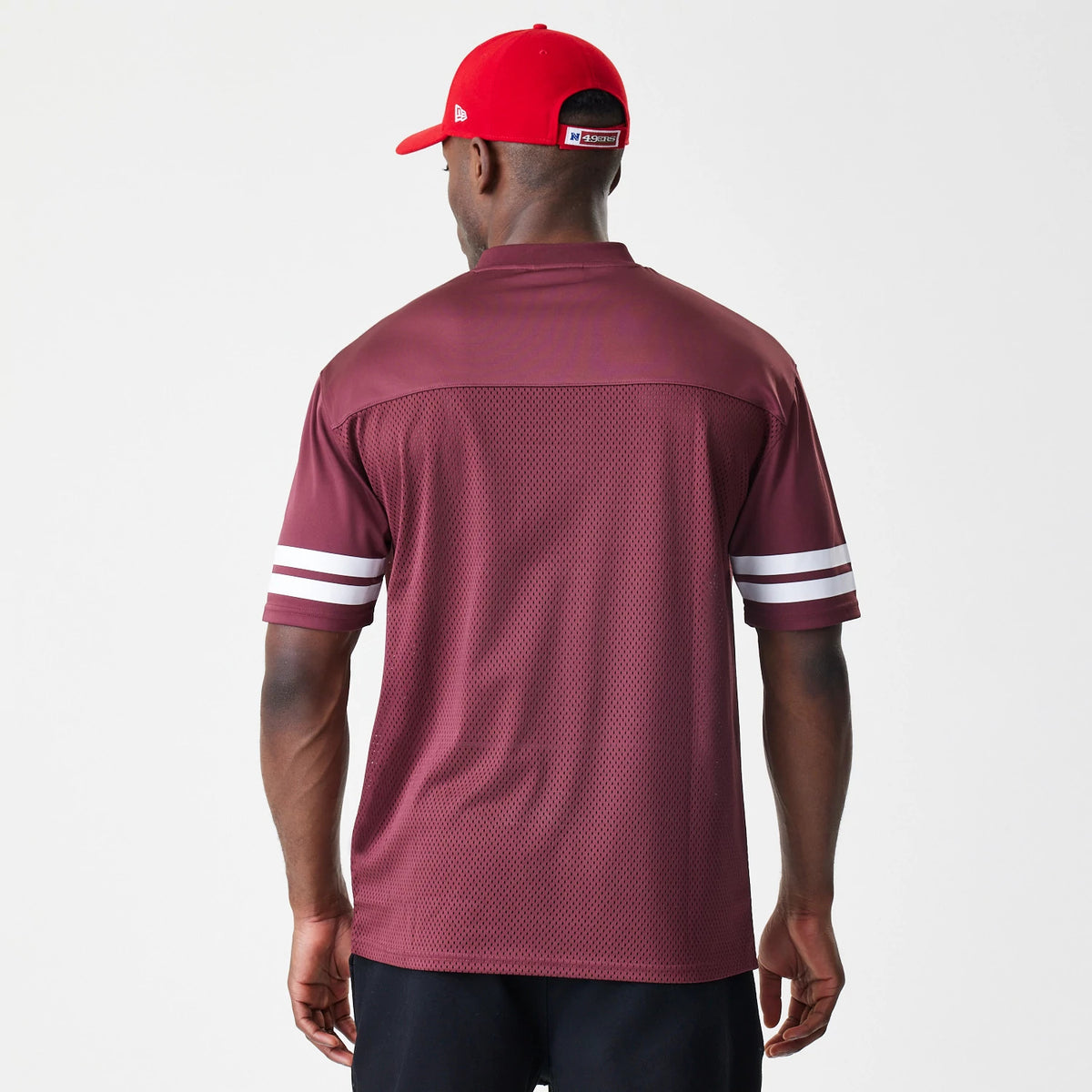 New Era San Francisco 49ers NFL Mesh Dark Red Jersey, rear view on a model showing the dark red mesh fabric with a yoke panel and contrasting white double stripes around the short sleeves.