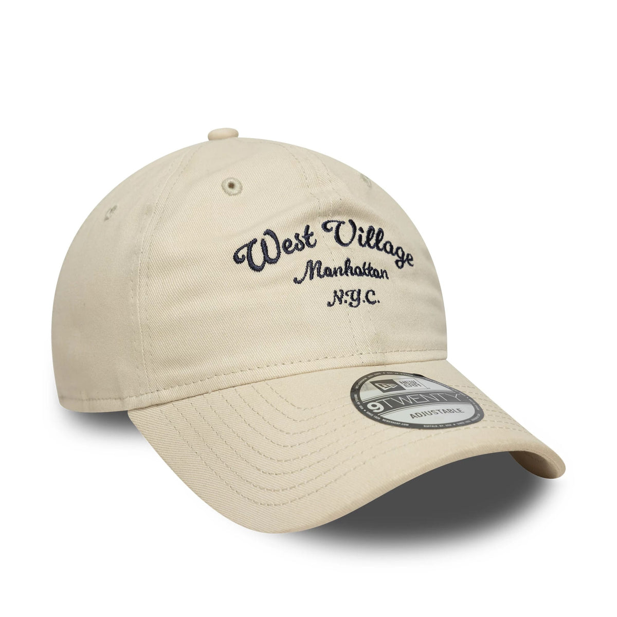 New Era Wordmark Cream 9TWENTY Adjustable Cap, three-quarter view showing navy embroidered West Village Manhattan N.Y.C. lettering on the front panel, with a curved cream visor featuring a 9TWENTY size sticker.