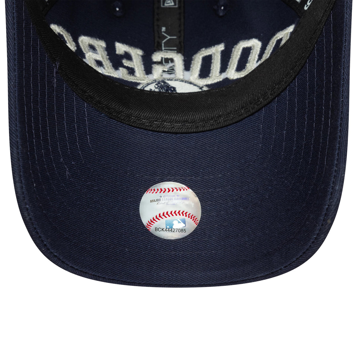 LA Dodgers Youth MLB College Navy New Era 9TWENTY Adjustable Cap, inside view showing the navy undervisor with a round MLB holographic authentication sticker and white embroidered Dodgers lettering under the black interior taping.