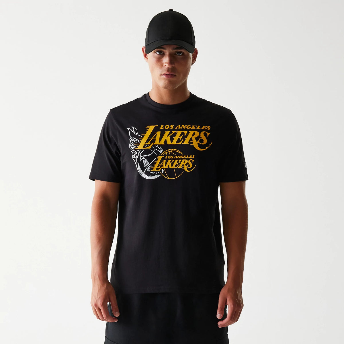New Era LA Lakers NBA Flame Graphic Black T-Shirt, front view on a model with a black cap, detailed with yellow Los Angeles Lakers branding across the chest and a large flame graphic on the side, enhancing the design.