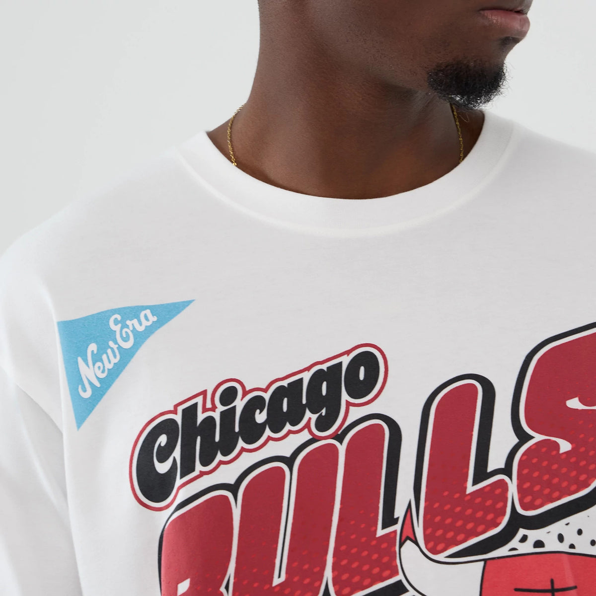 New Era Chicago Bulls NBA Lifestyle Graphic White T-Shirt, front view on a model showing red and black Bulls lettering with a graphic bull logo, and a blue New Era printed logo on the top left of the chest.