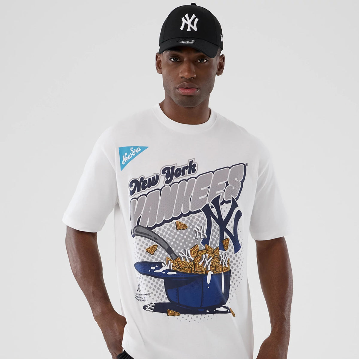 New Era New York Yankees MLB Lifestyle Graphic White T-Shirt, front view on-model showing a large graphic with blue and grey New York Yankees text, a pot of gold artwork on the chest, and a blue printed New Era logo on the left chest.
