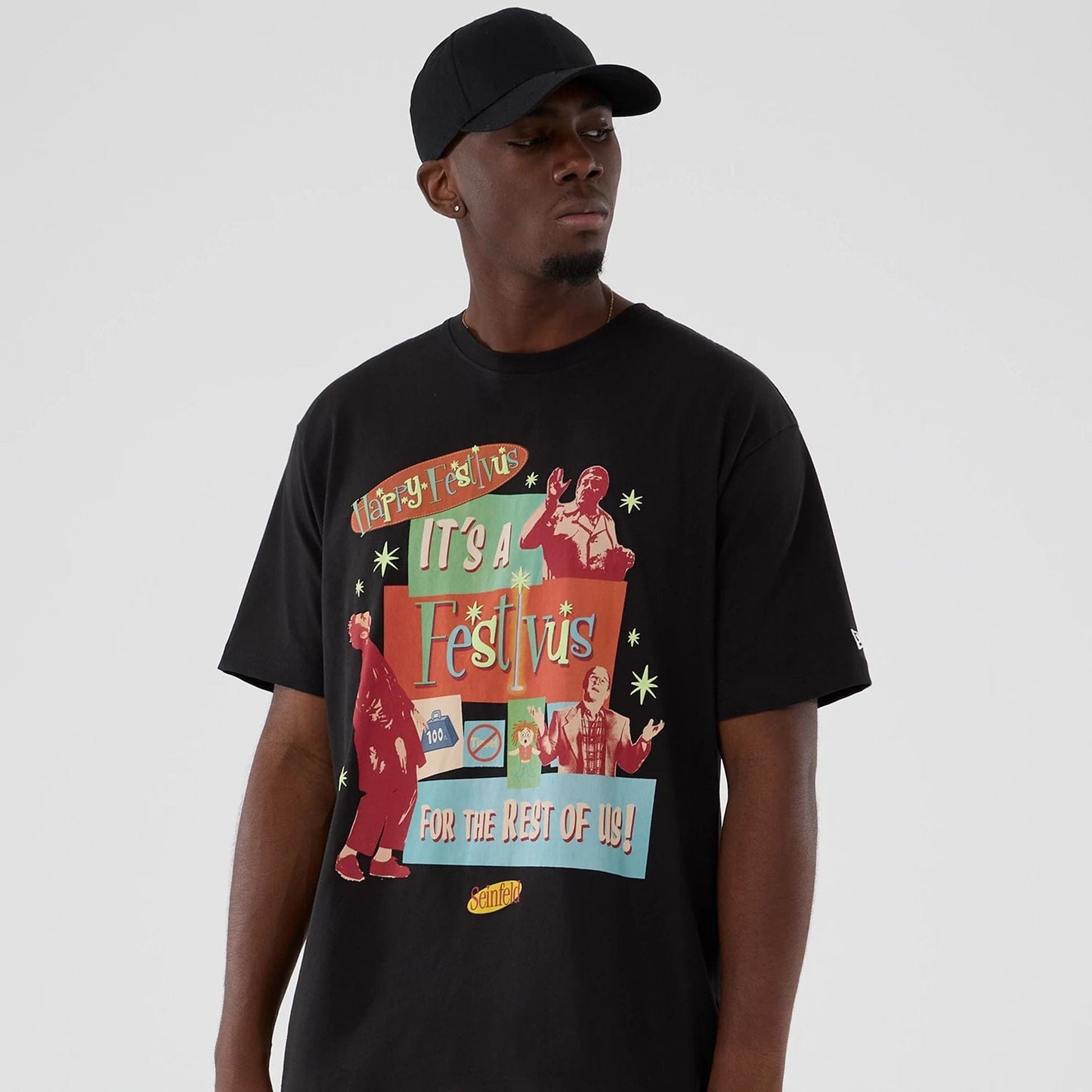 New Era Seinfeld Lifestyle Graphic Black T-Shirt, front view on-model displaying graphics with Happy Festivus It's A Festivus For The Rest Of Us! text across the chest, and a printed New Era logo on the sleeve.